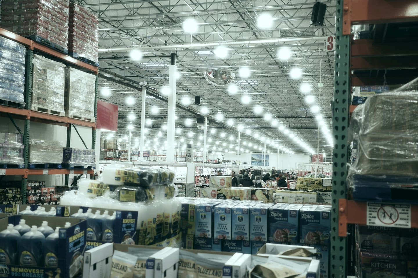 Clienti che guardano tra gli scaffali alti di un grande magazzino luminoso.